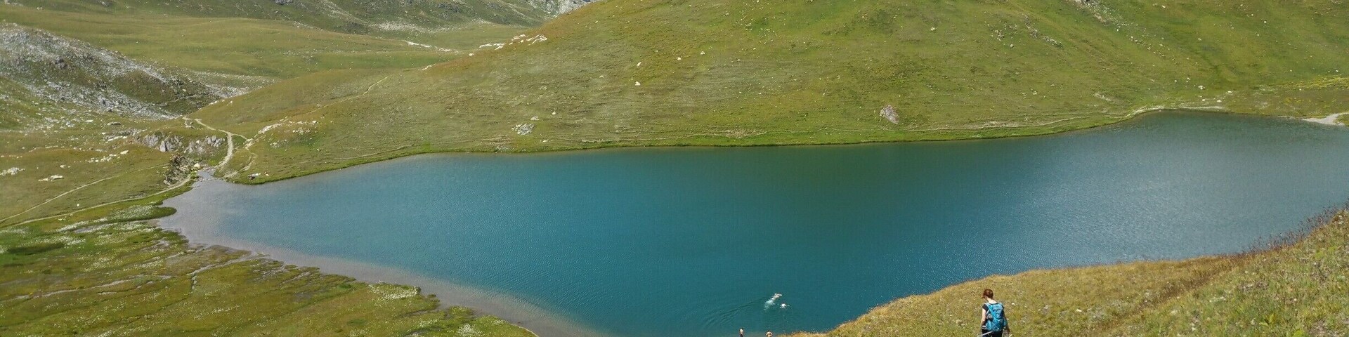 A mountain landscape with a lake and hikers.