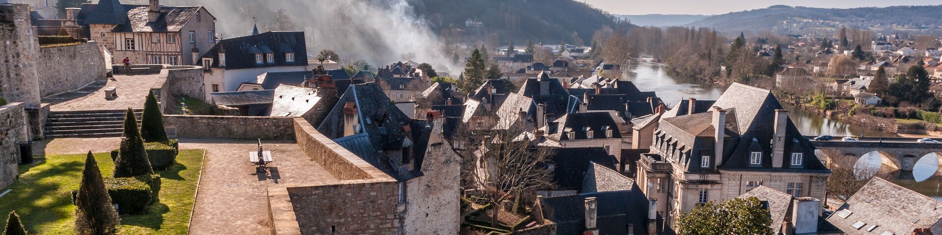 A historic town with a castle, cobblestone streets, and a river.