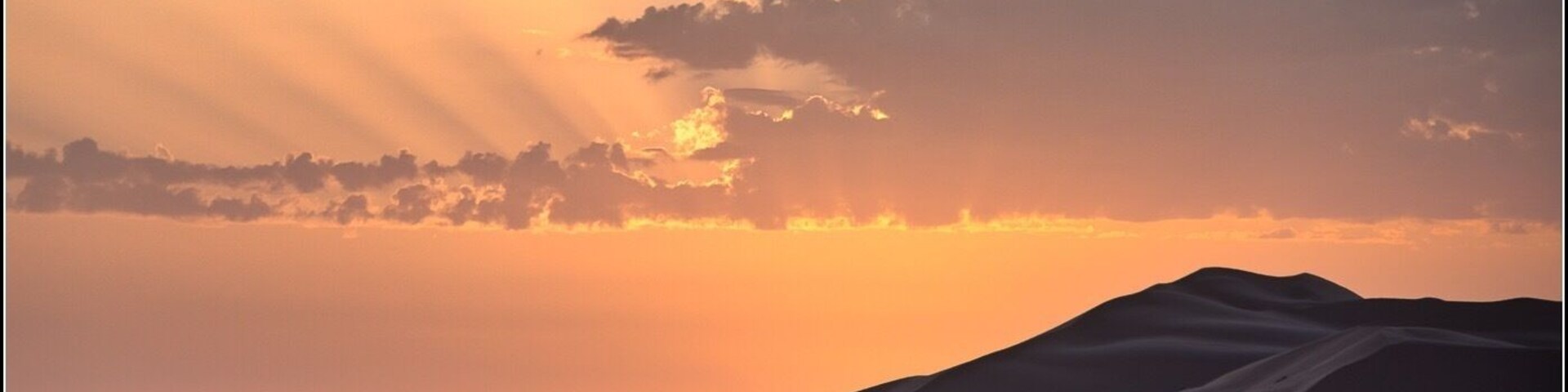 Paisaje desértico con dunas de arena y un atardecer.