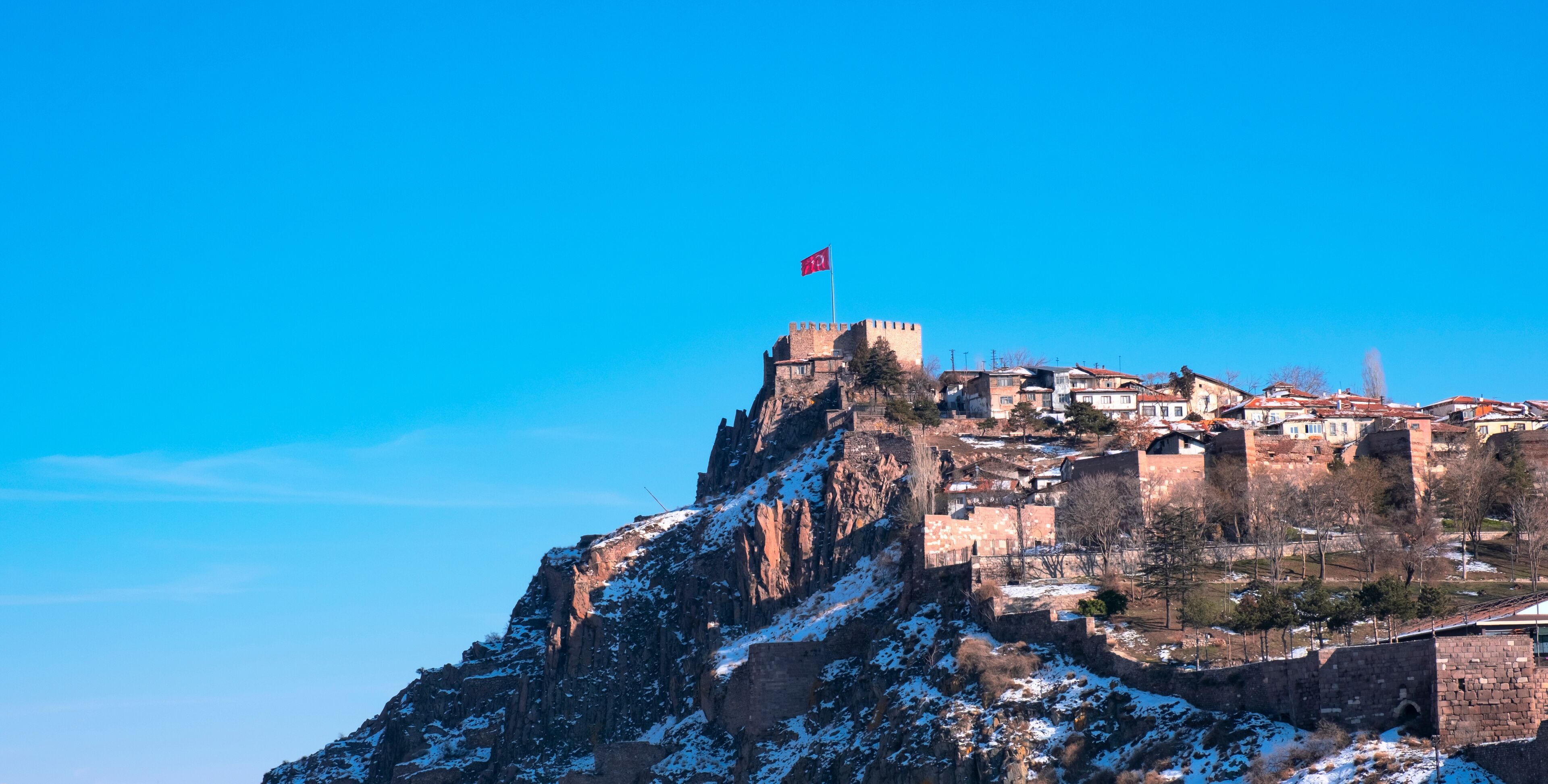 A snow-covered mountain with a castle and flag on top.