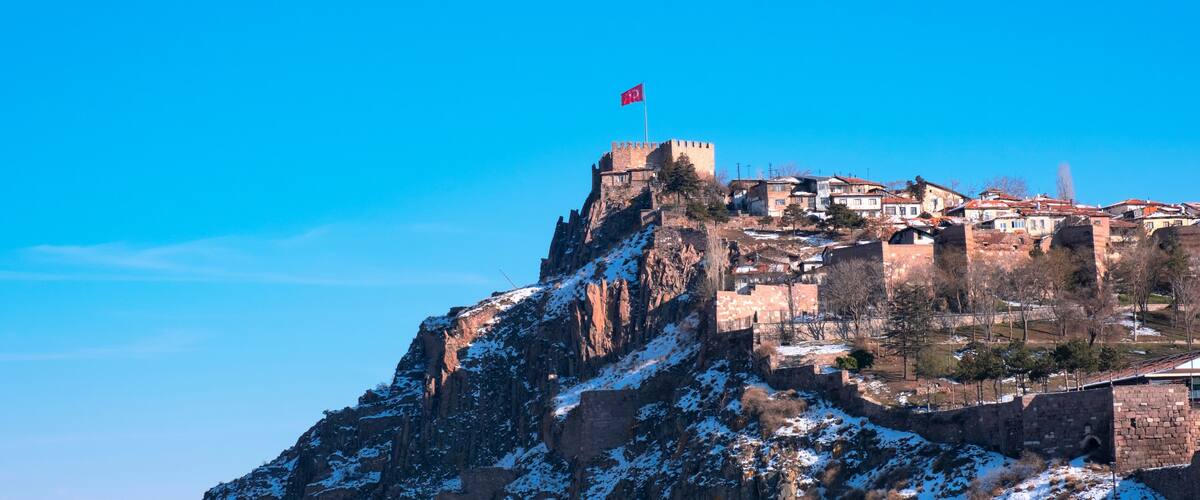 A snow-covered mountain with a castle and flag on top.