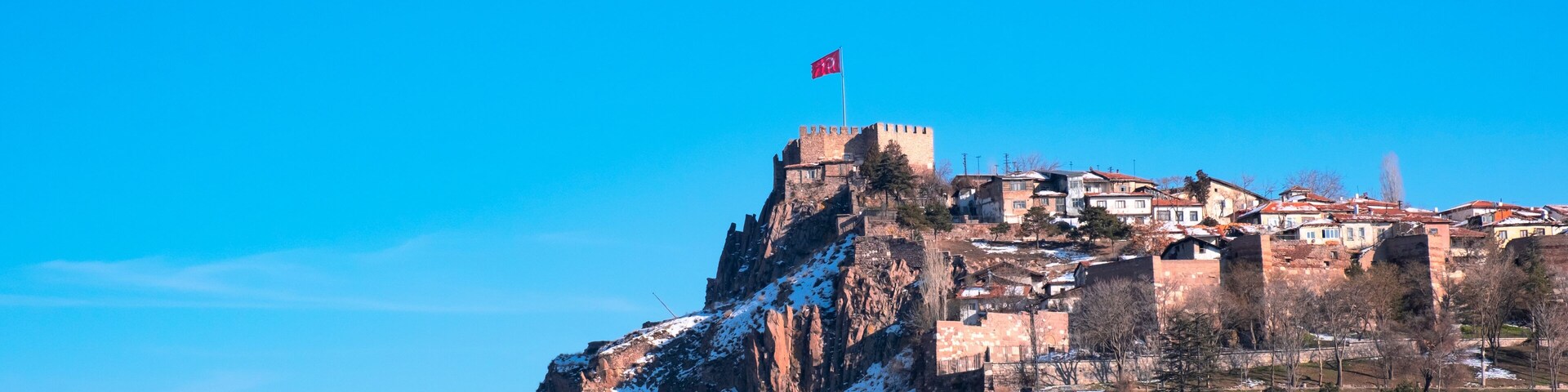 A snow-covered mountain with a castle and flag on top.