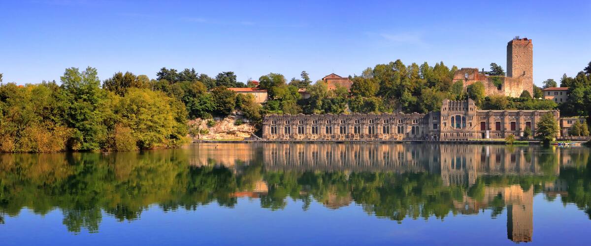 A historic castle with a tower and a reflection in the water.