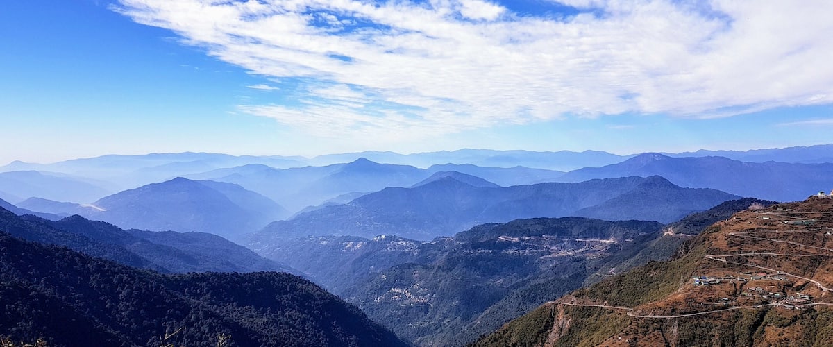 A mountainous landscape with a clear sky and distant mountain ranges.