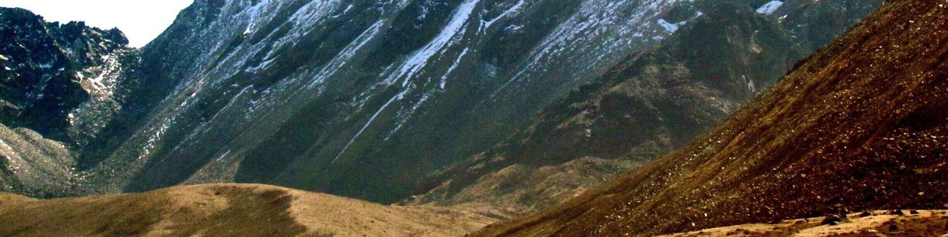 A rugged mountain landscape with snow-capped peaks and a valley.