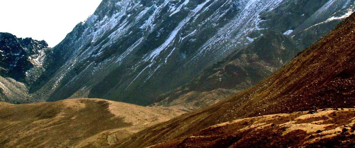 A rugged mountain landscape with snow-capped peaks and a valley.