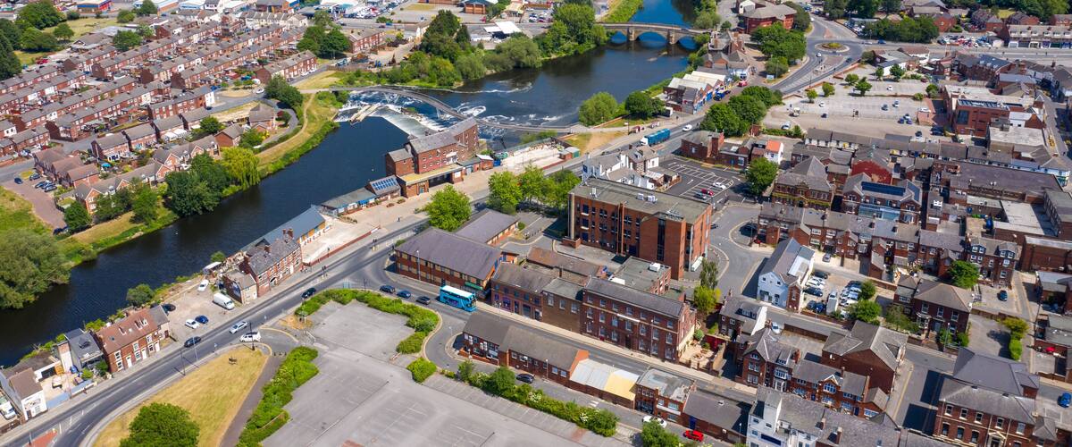 An aerial view of a riverside town with residential areas, a bridge, and industrial buildings.