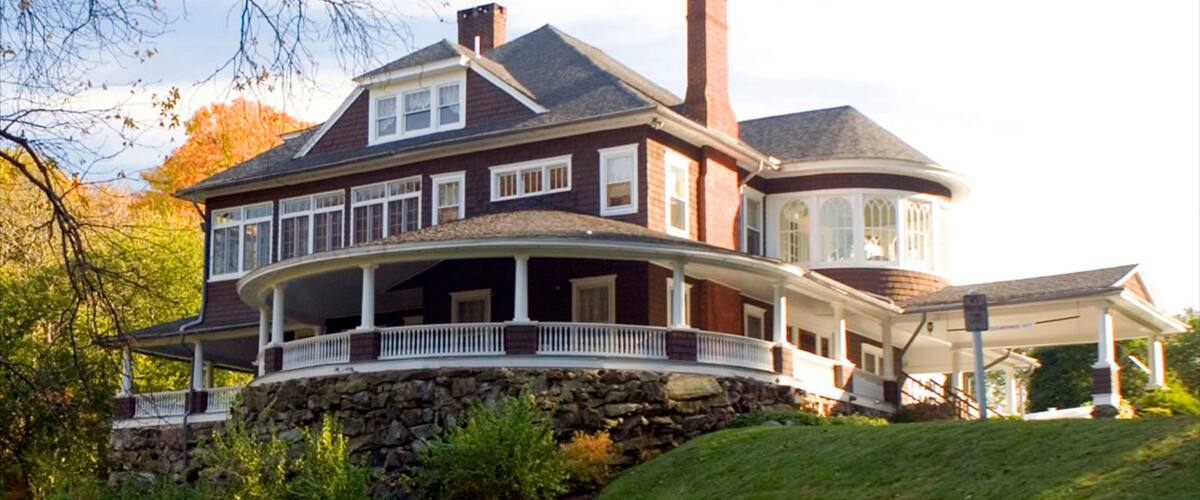 A large, two-story house with a wrap-around porch and stone foundation.