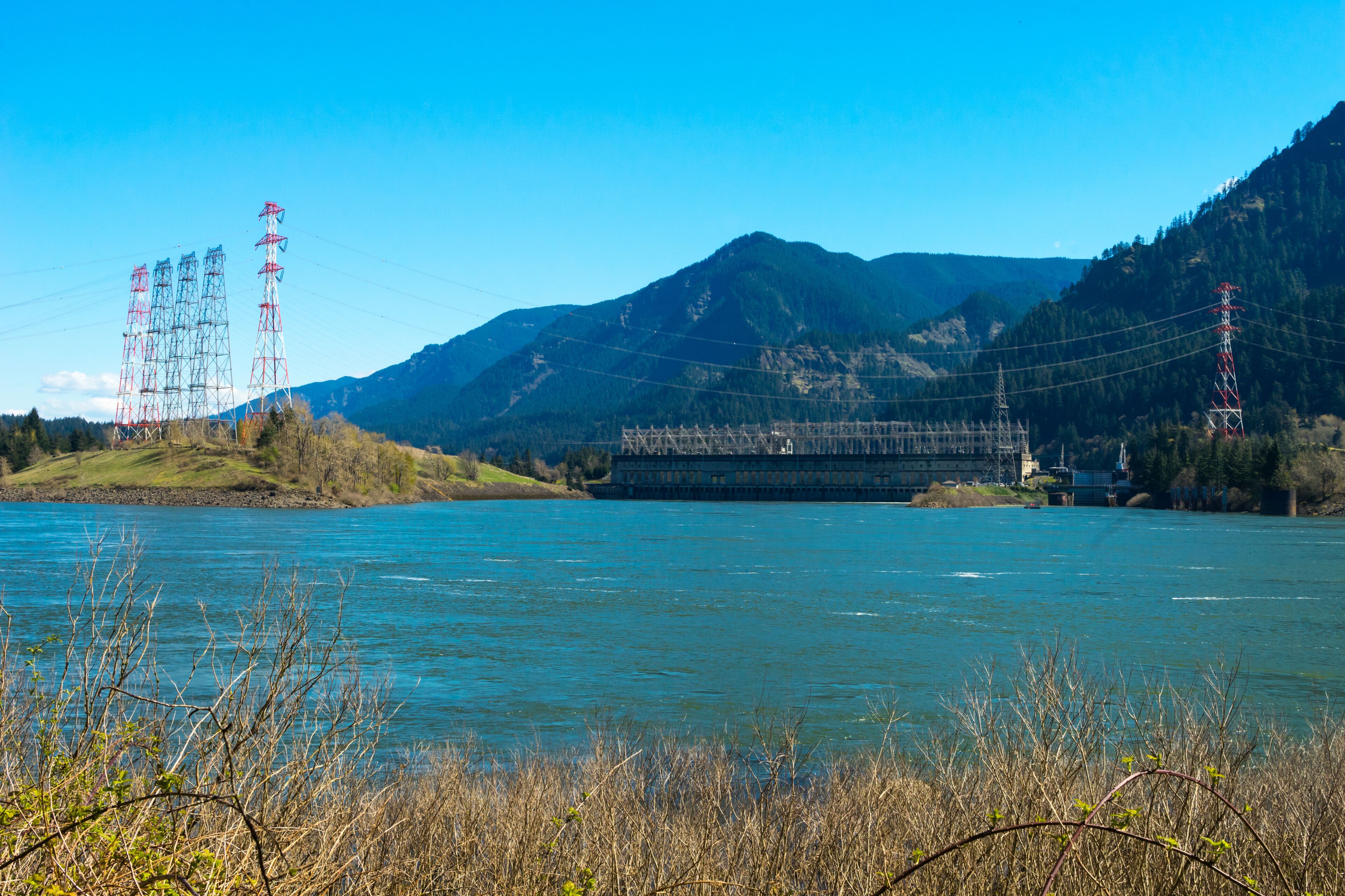 A river with mountains in the background and power lines on the left.