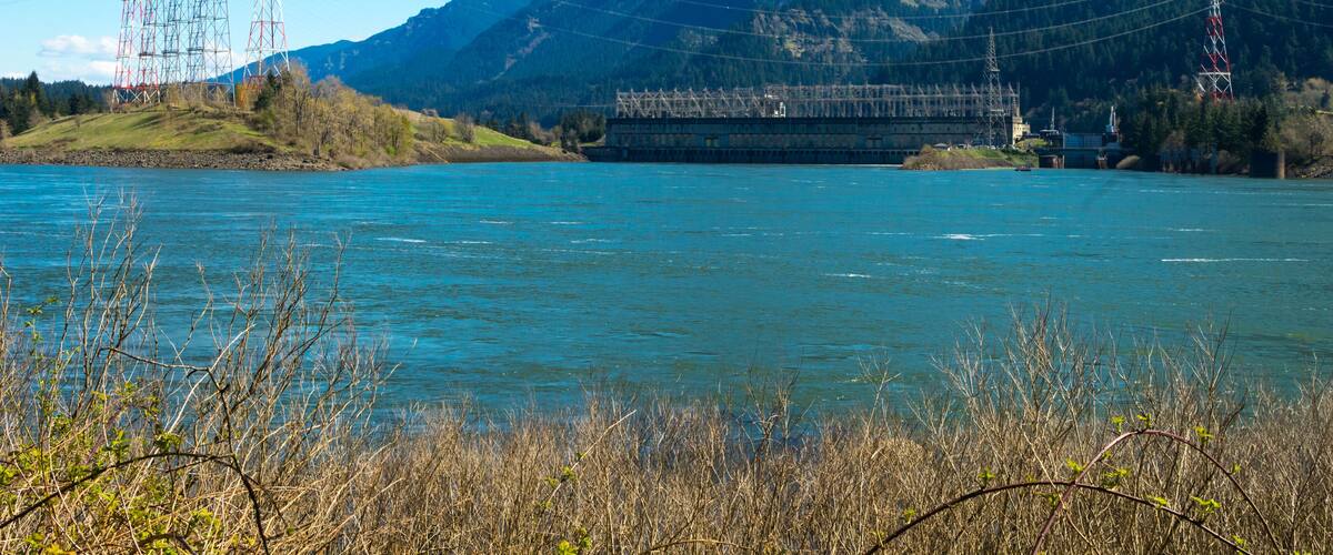 A river with mountains in the background and power lines on the left.
