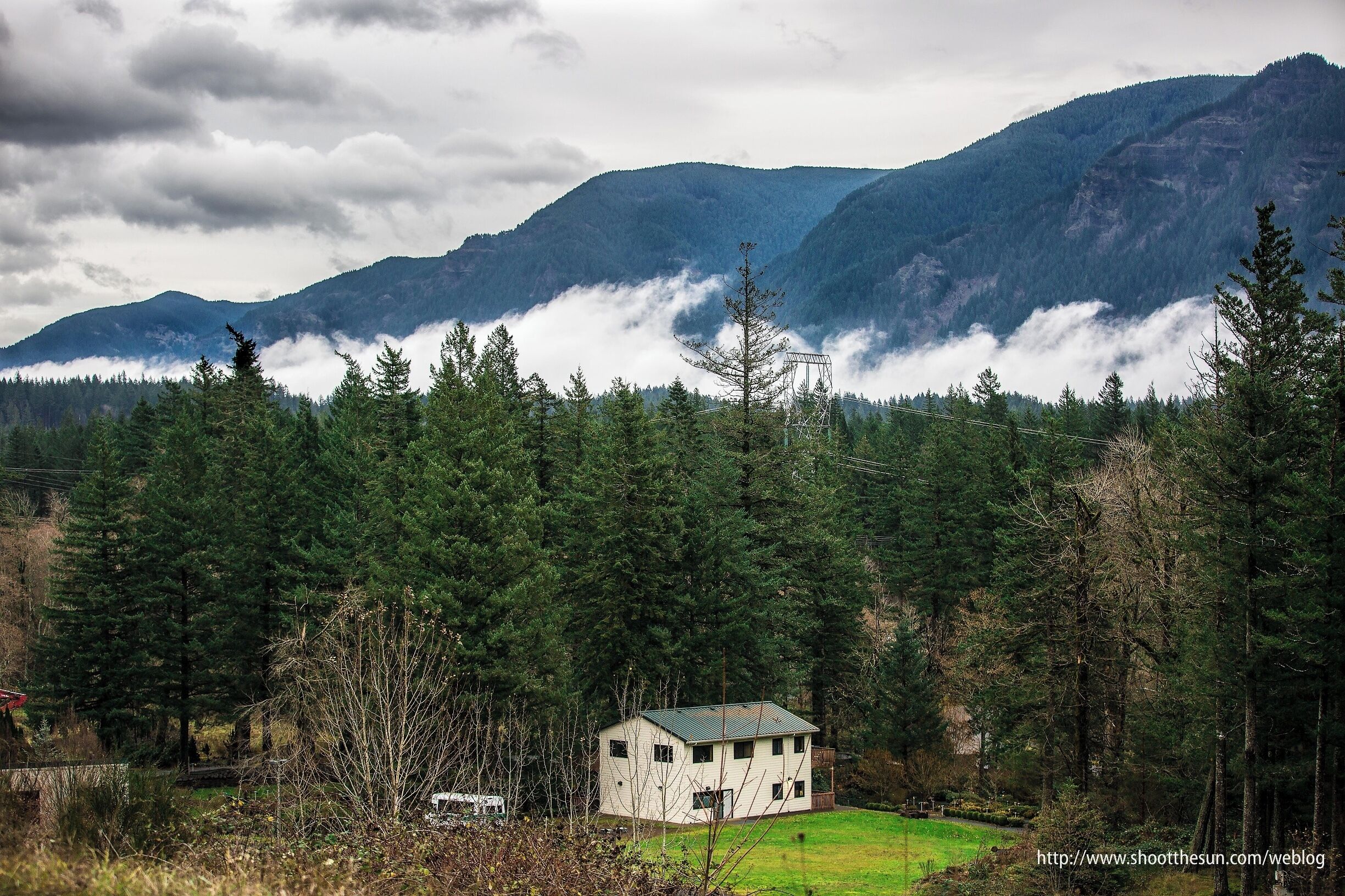 A house surrounded by dense forest and mountains.