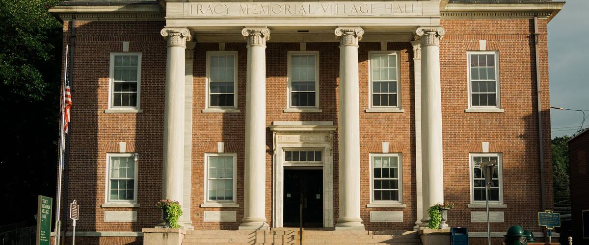 A brick building with a green dome and columns, labeled "TRACY MEMORIAL VILLAGE HALL".