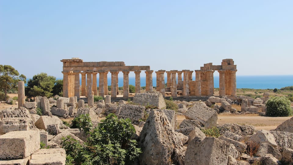 Ancient ruins with columns and scattered stones.