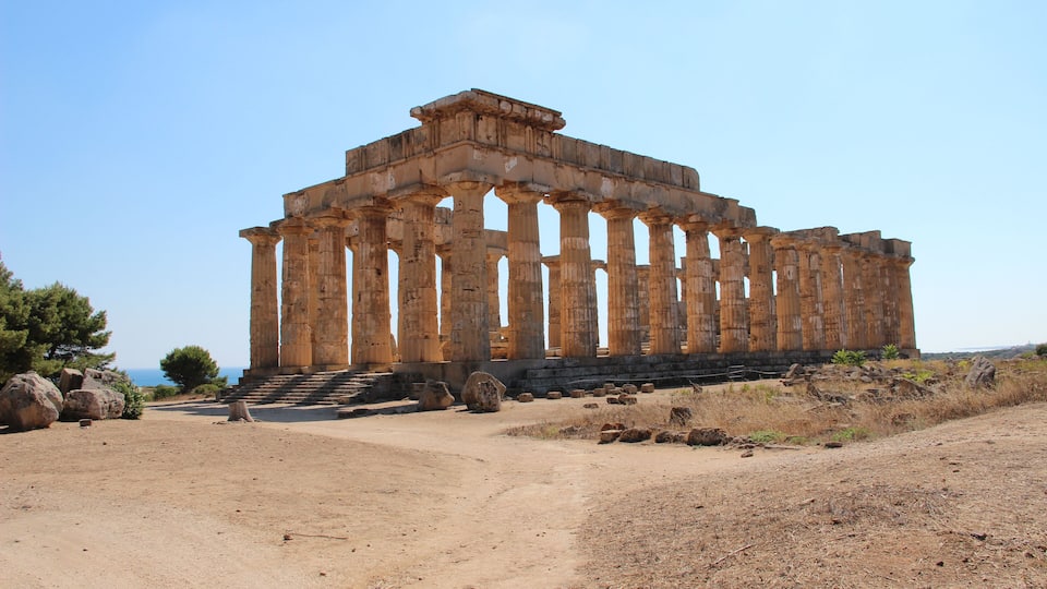 An ancient Greek temple with columns and a staircase leading up to the entrance.