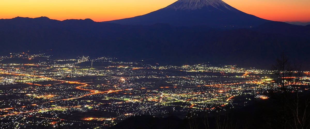 A cityscape at dusk with a mountain in the background.