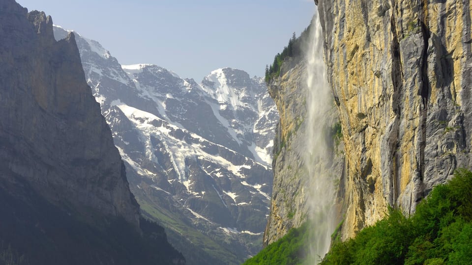 A mountain landscape with a waterfall cascading down a steep cliff.