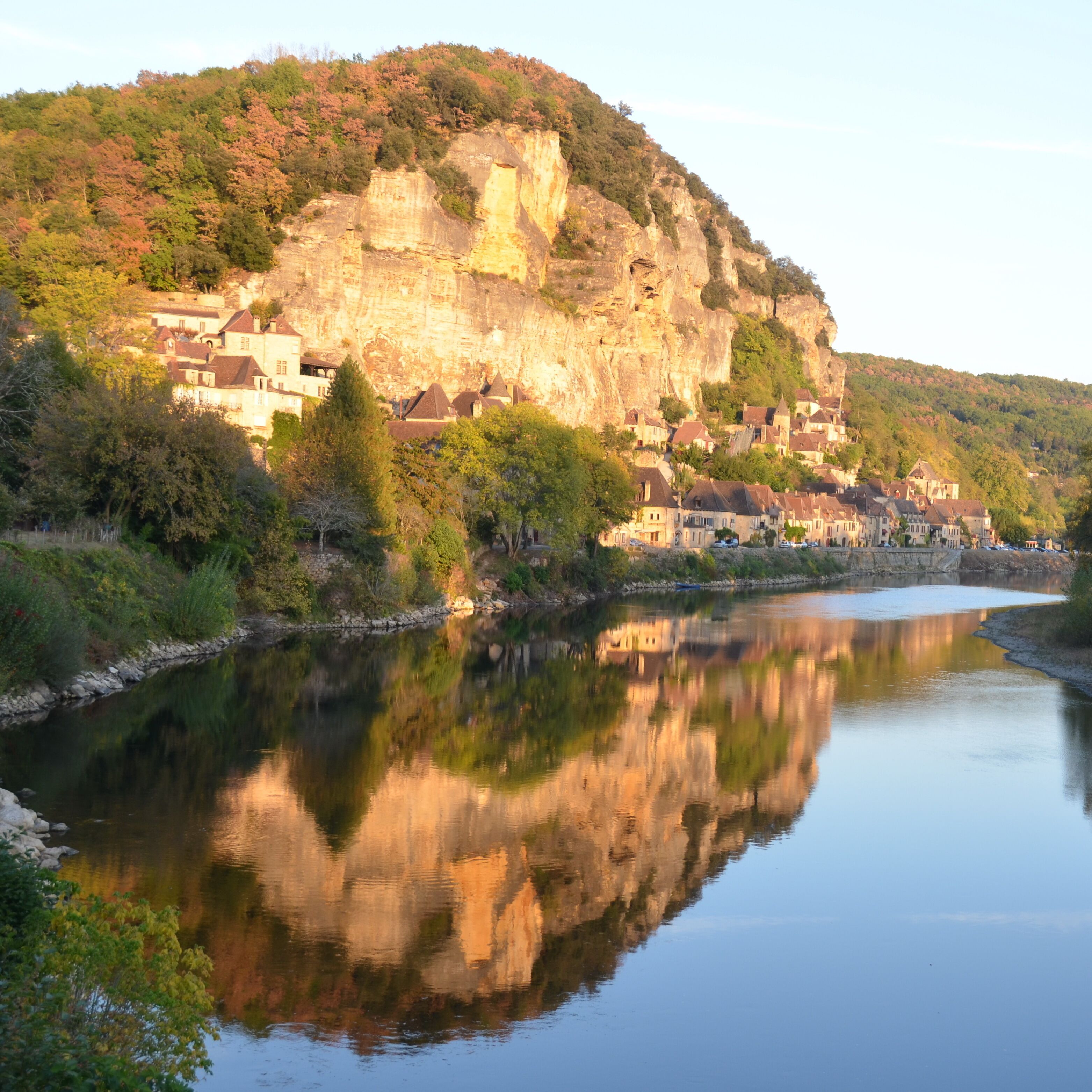 View Eastwards at La Roque-Cageac along the Dordogneriver, with nice rocqu reflections in the eveningsun