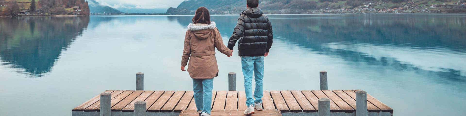 Travelers couple look at the mountain lake in Iseltwald jetty at Lake Brienz in Switzerland, Travel and active life concept