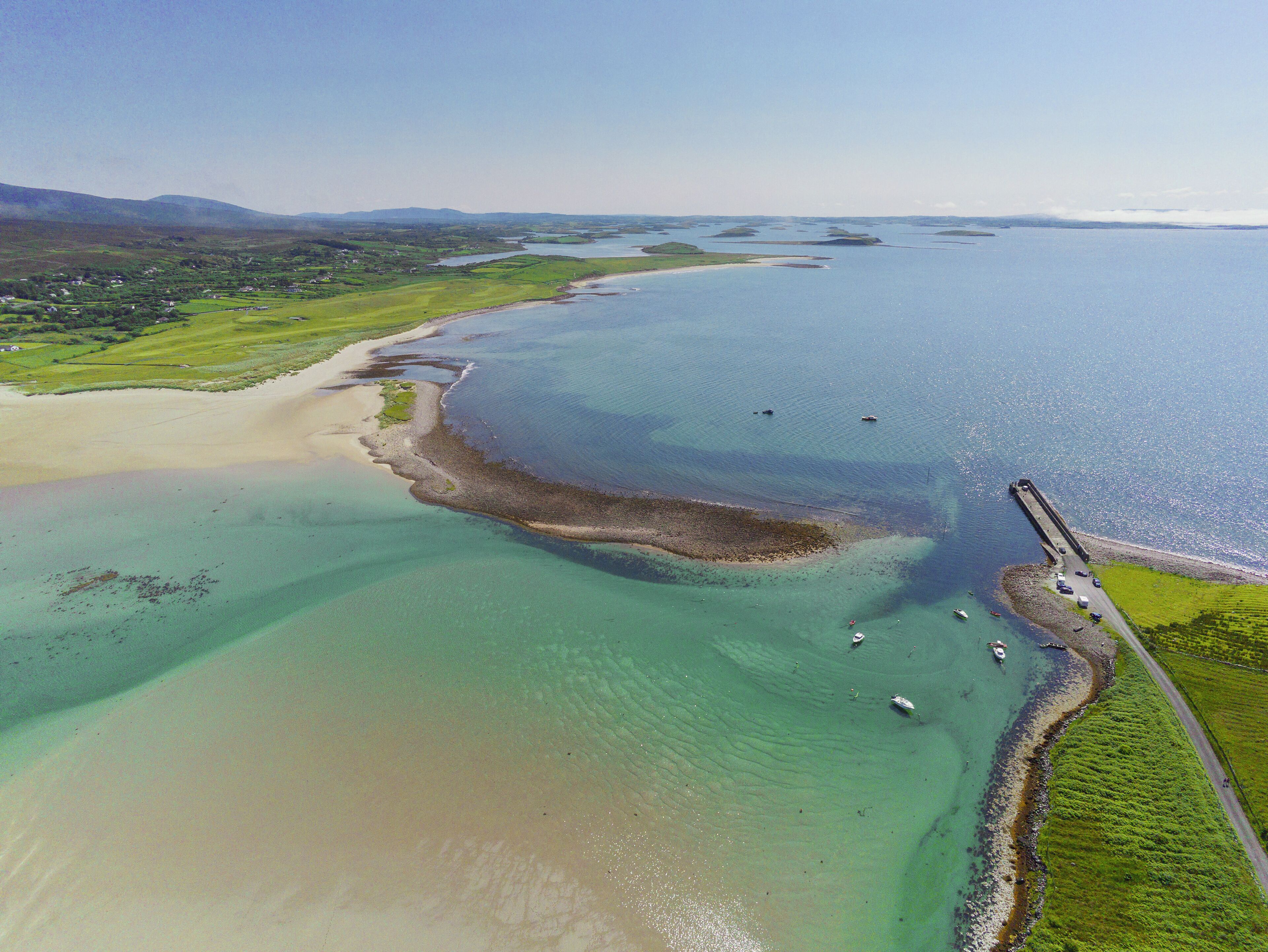 Aerial drone view on a Mulranny pier in county Mayo, Ireland Warm sunny day. Rich saturated blue color of water and sky. Travel and tourism. Irish nature landscape scene.