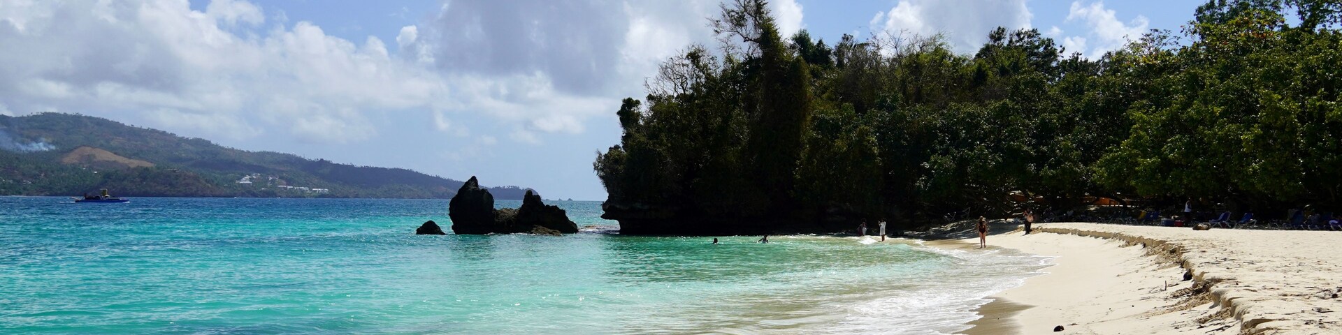 Uma praia com águas turquesa cristalinas, areia dourada e um cenário de árvores verdes exuberantes.
