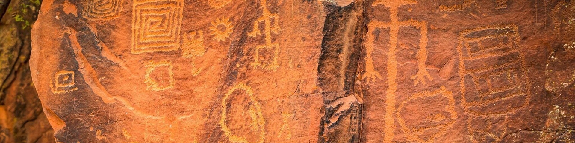 Una roca con antiguas petroglyfos, incluyendo formas geométricas y símbolos.
