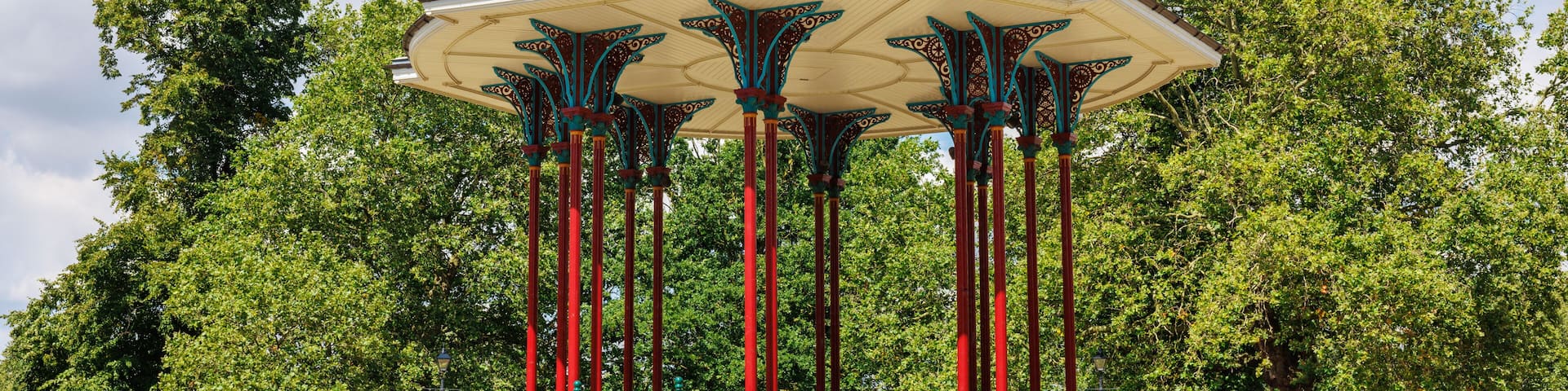 A gazebo with a domed roof and ornate columns, surrounded by trees.