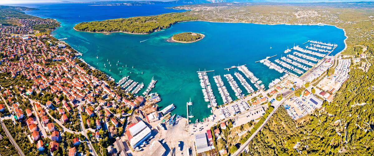 An aerial view of a coastal town with a marina, dense residential area, and a large body of water.