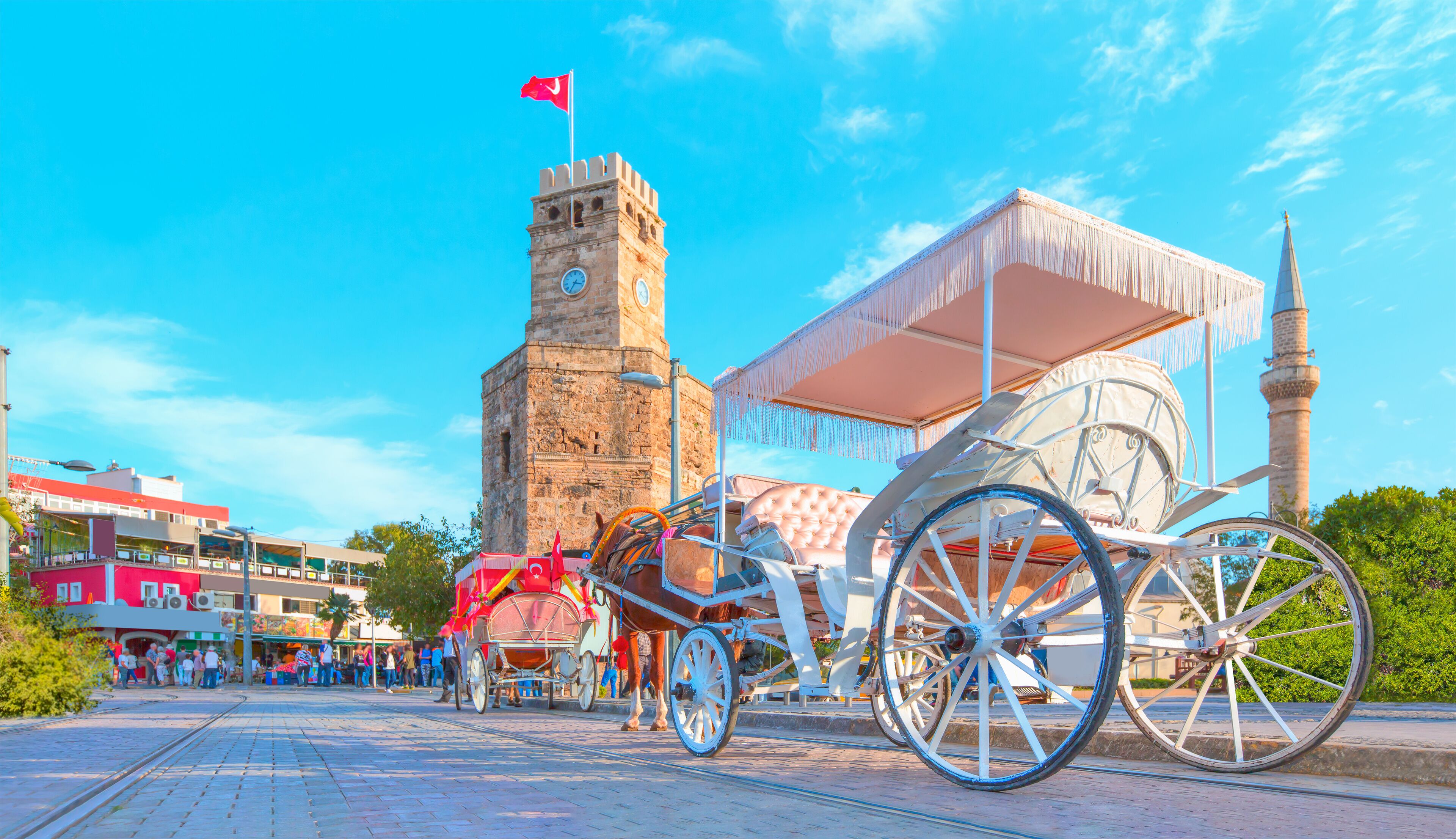 Una torre del reloj histórica, un carruaje tirado por caballos tradicional y una mezquita con un minarete.