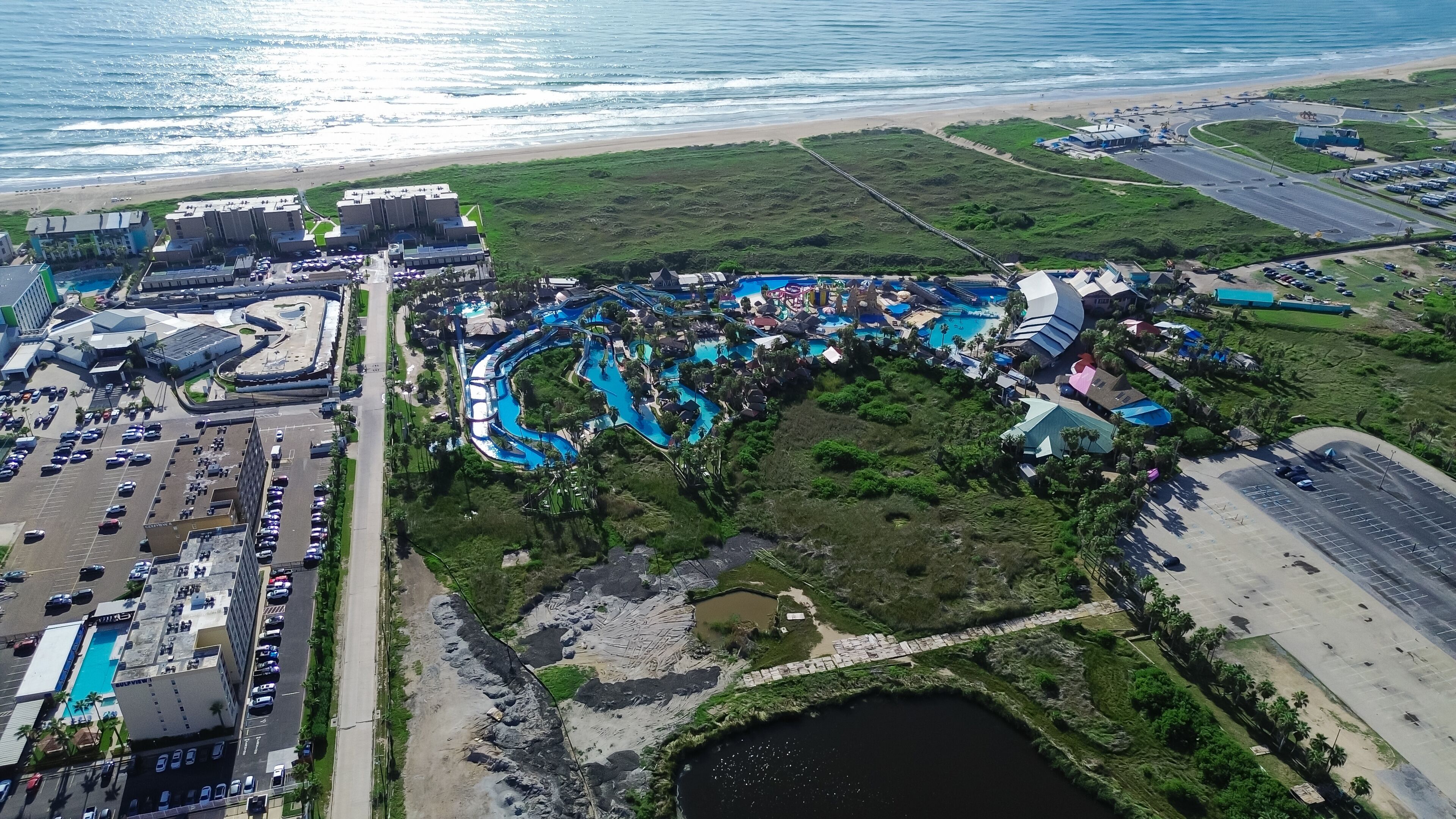 Large waterpark near Isla Blanca Beach in resort town South Padre Island, tropical white sandy beaches with high-rise condos, beach-front hotels, vacation rentals, coastal lagoons, aerial view