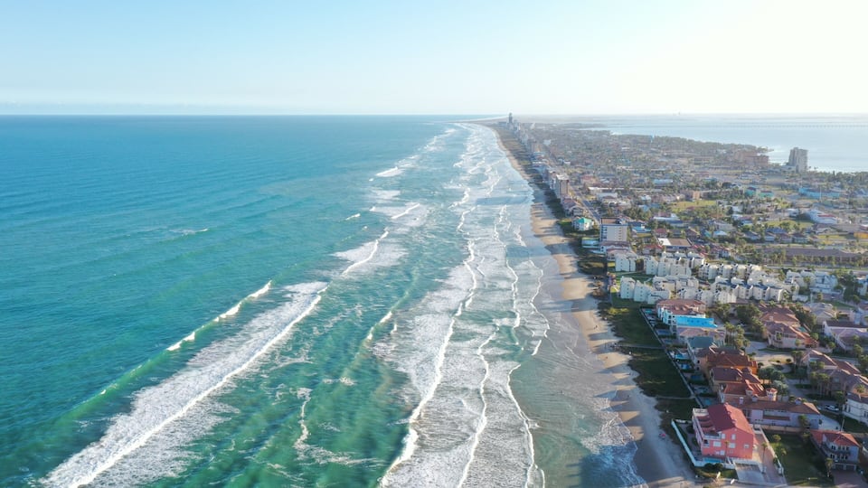 A coastal city with a beach and residential buildings along the shoreline.