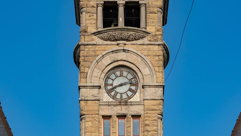 A clock tower with a pointed roof and stone construction.