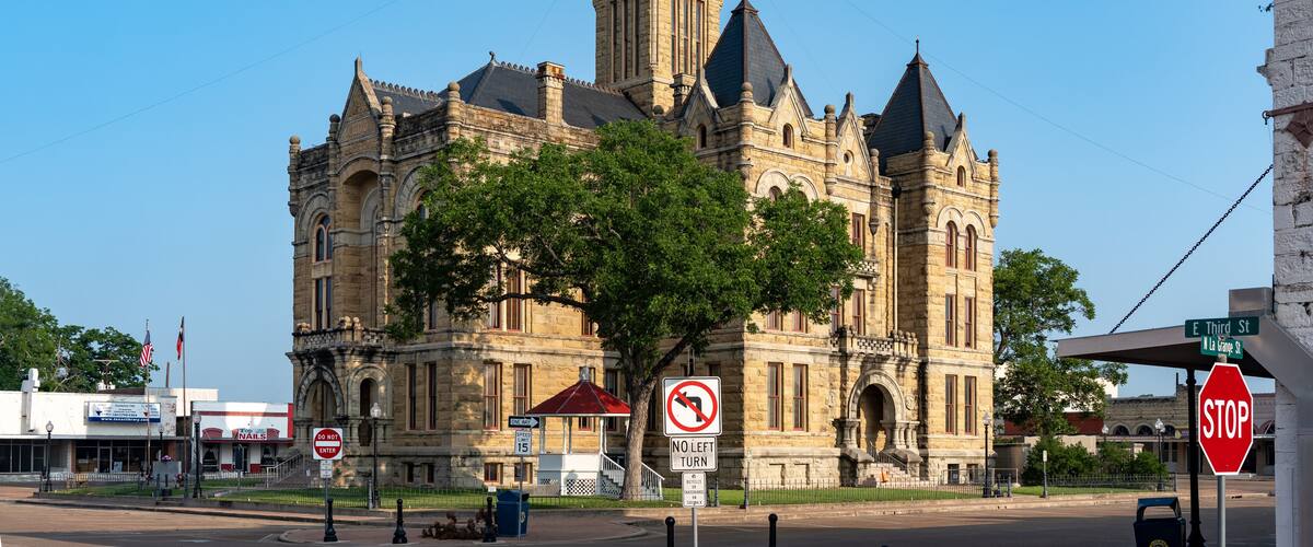 A historic building with a clock tower, a no left turn sign, and a stop sign.