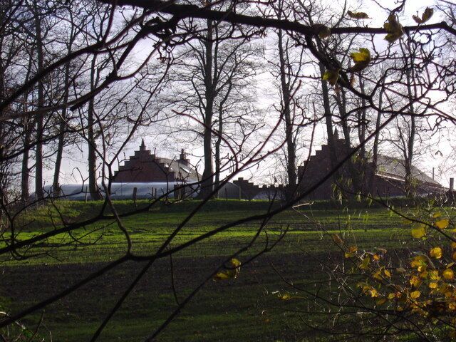 Un parque con un edificio tradicional, árboles sin hojas y un campo cubierto de césped.