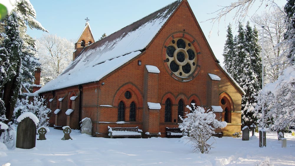 A snow-covered church with a large circular window and a steeple.