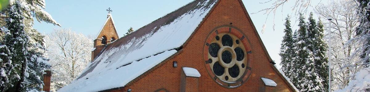 Eine schneebedeckte Kirche mit einem großen Rundfenster und einem Kirchturm.