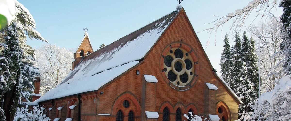 A snow-covered church with a large circular window and a steeple.