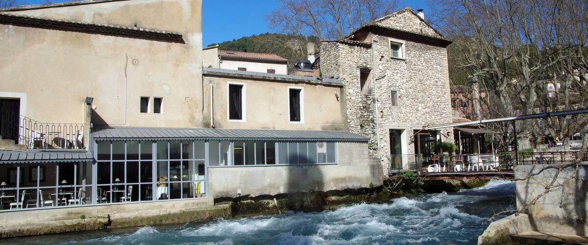 A river flowing through a town with buildings and a stone tower.