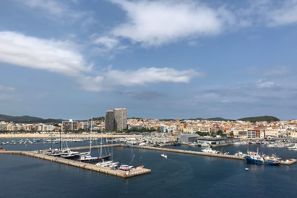 A coastal cityscape with a marina, boats, and buildings.