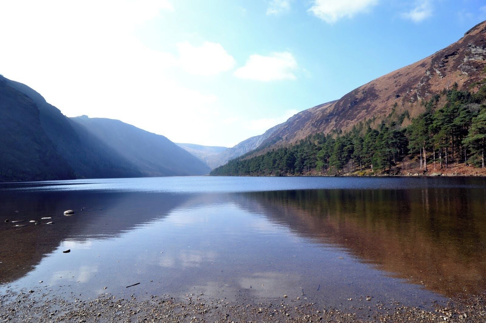 Um lago tranquilo rodeado por montanhas e florestas densas.