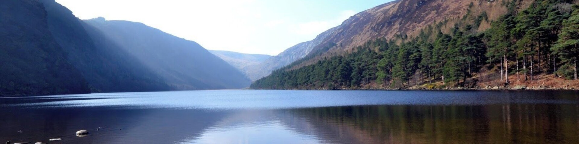 Um lago tranquilo rodeado por montanhas e florestas densas.