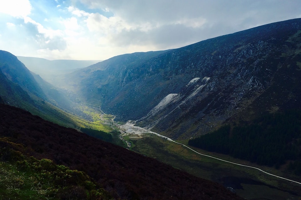 A mountainous landscape with a valley and a winding road.
