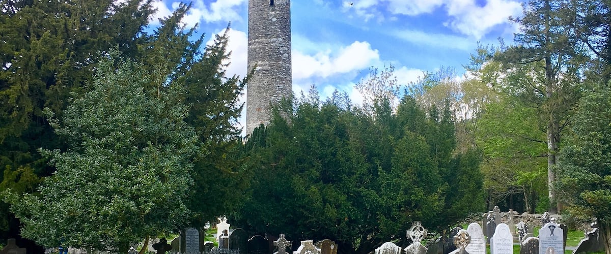 A cemetery with gravestones and a tall stone tower.