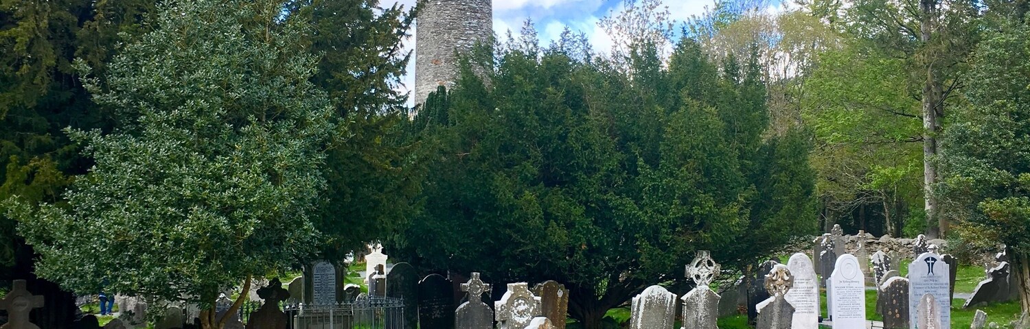 Un cementerio con lápidas y una alta torre de piedra.