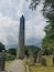 A tall stone tower in a cemetery with gravestones and a path leading to it.