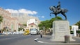 A statue of a man on a horse, a church, and a mountain in the background.