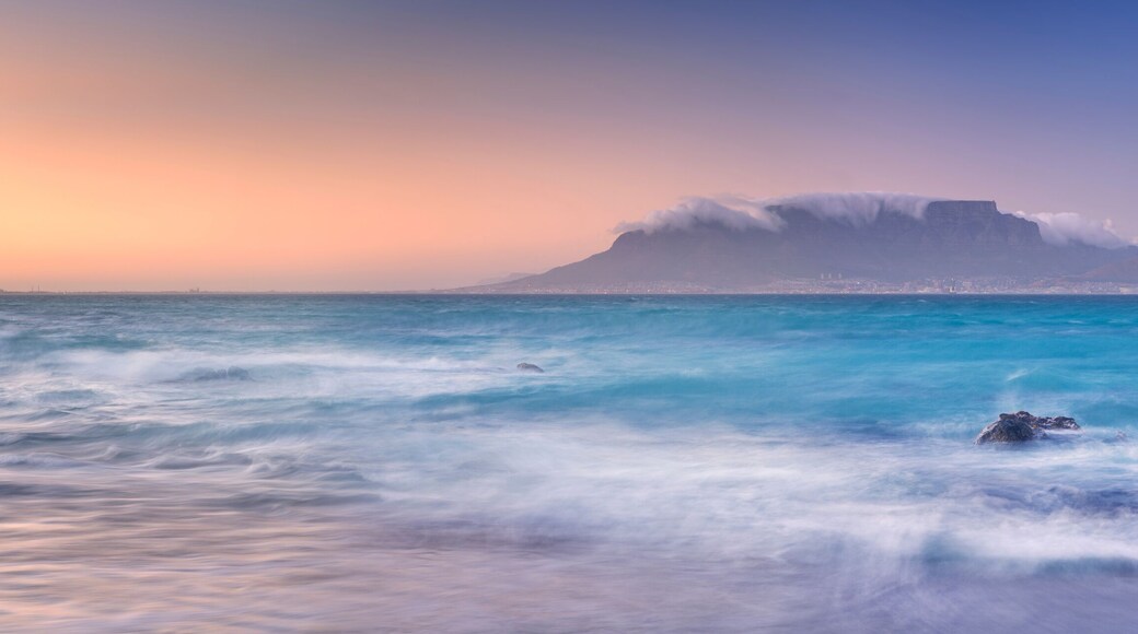 Un paisaje costero con una montaña destacada y olas del océano.
