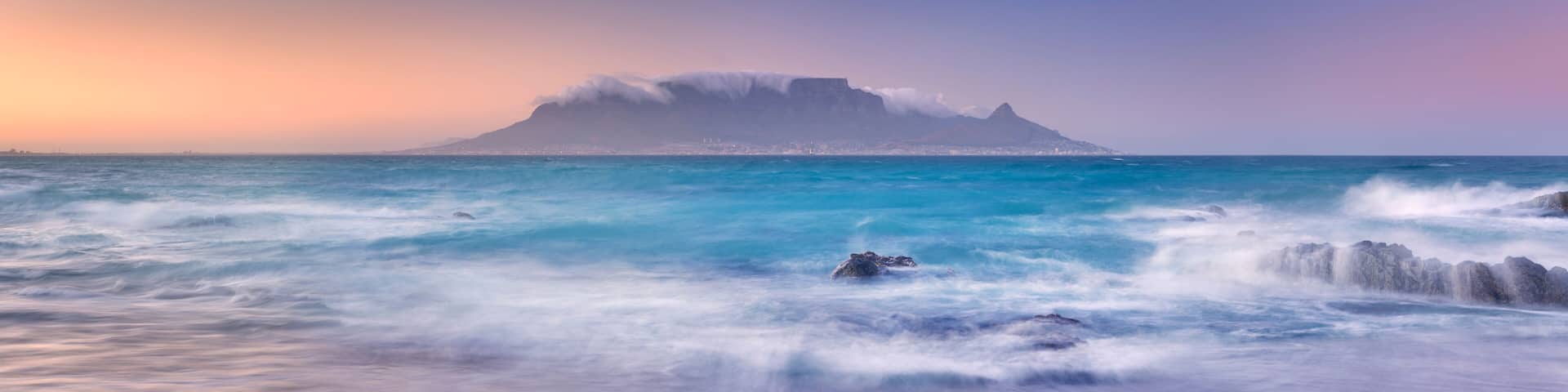 A coastal landscape with a prominent mountain and ocean waves.