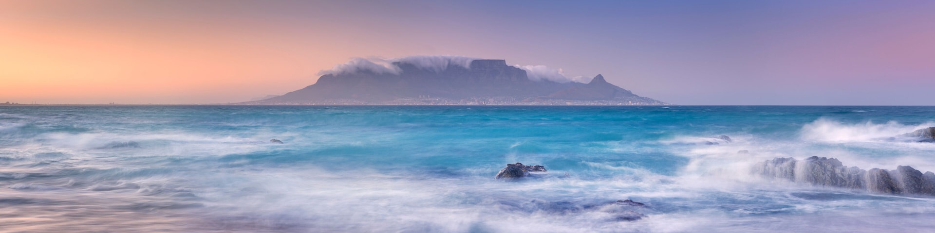 A coastal landscape with a prominent mountain and ocean waves.