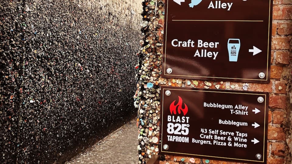 Eine Ziegelwand mit einem Schild, das den Weg zu Bubblegum Alley, Craft Beer Alley und einem Taproom namens Blast 825° weist, der Selbstbedienungszapfhähne für Craft Beer und Wein hat.