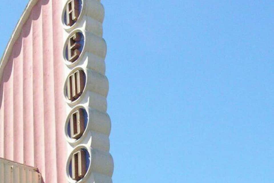 A pink and white building with a row of circular windows and a decorative finial.